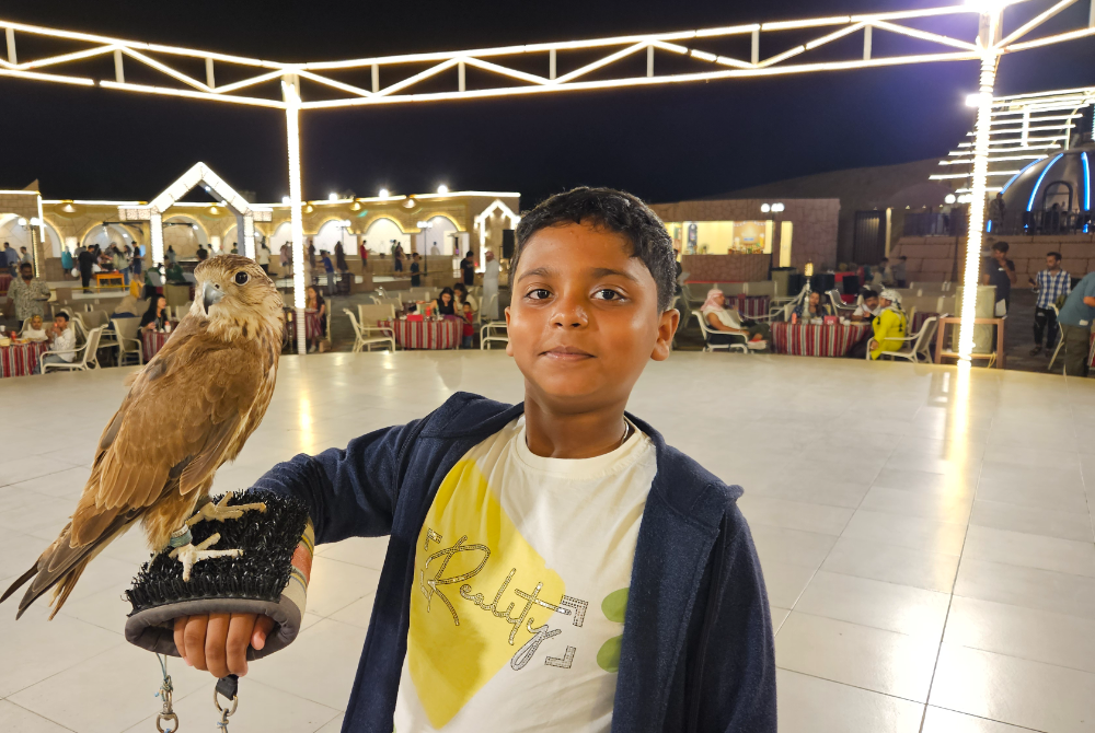 Devansh holding a falcon in the Dubai desert